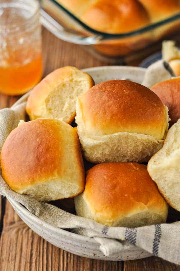 Basket of homemade soft dinner rolls served on a wooden table