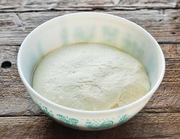 Dinner roll dough rising in a bowl