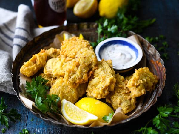 Horizontal shot of a plate of southern fried oysters with lemon wedges and sauce