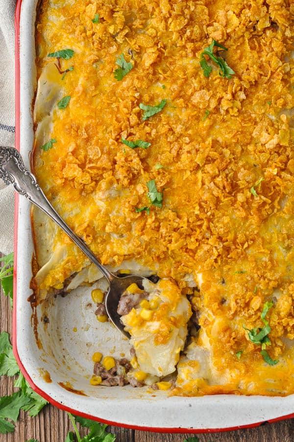 Overhead shot of a spoon in a pan of Ground Beef and Potato Casserole with Corn Flake topping