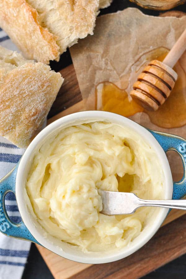 Knife in a bowl of whipped honey butter with honey dipper on the side