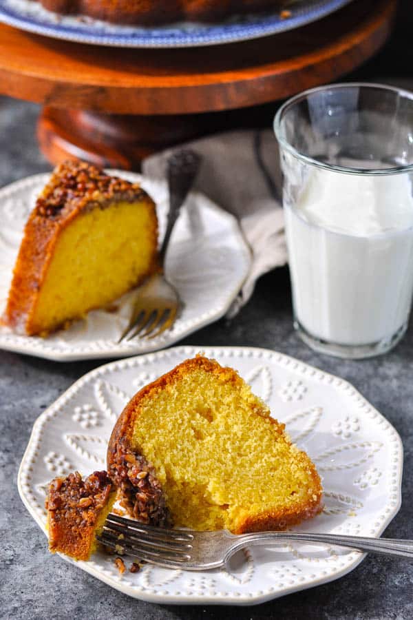 Two slices of golden rum cake on white plates