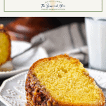Front shot of a slice of Caribbean rum cake on a plate with milk in the background and a text title box at the top