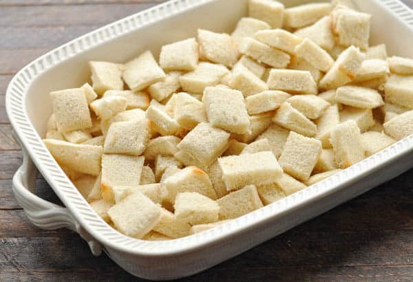 Cubed bread in the bottom of a white baking dish