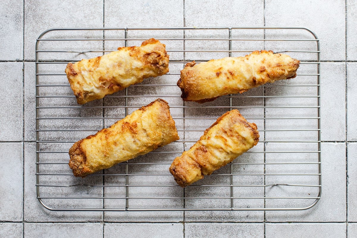 Fried fish draining on a wire rack.