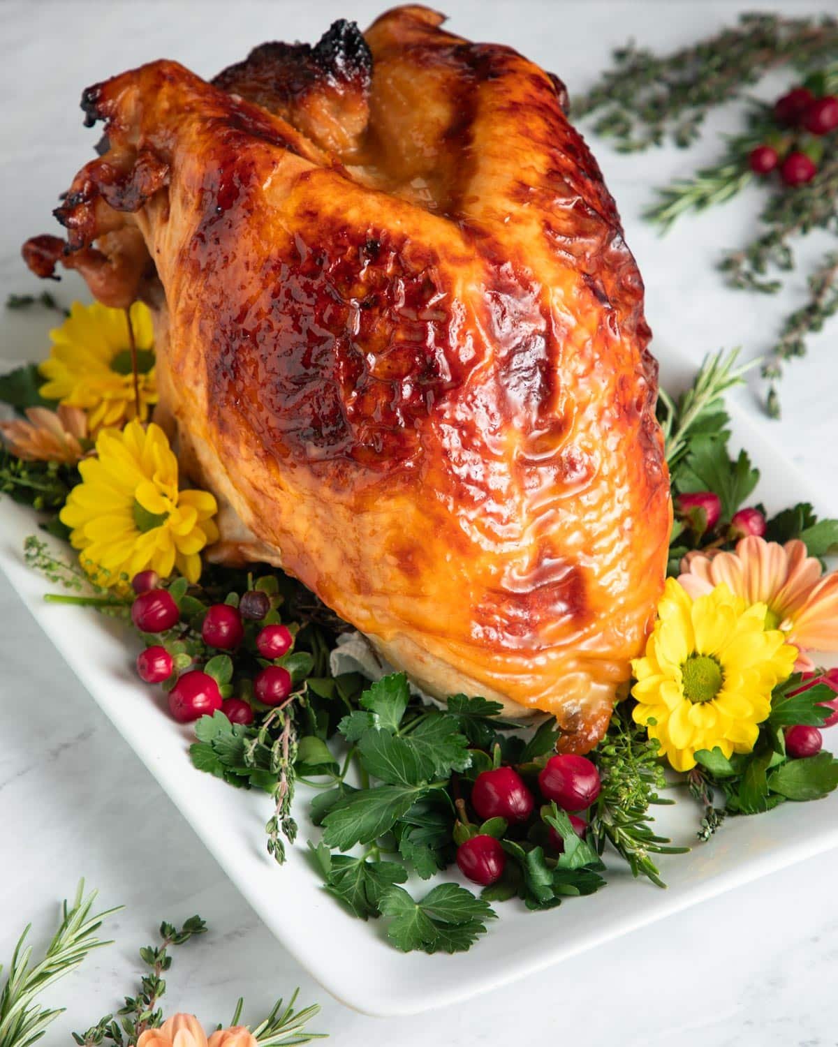 Side shot of a roasted maple glazed whole turkey breast on a serving platter.
