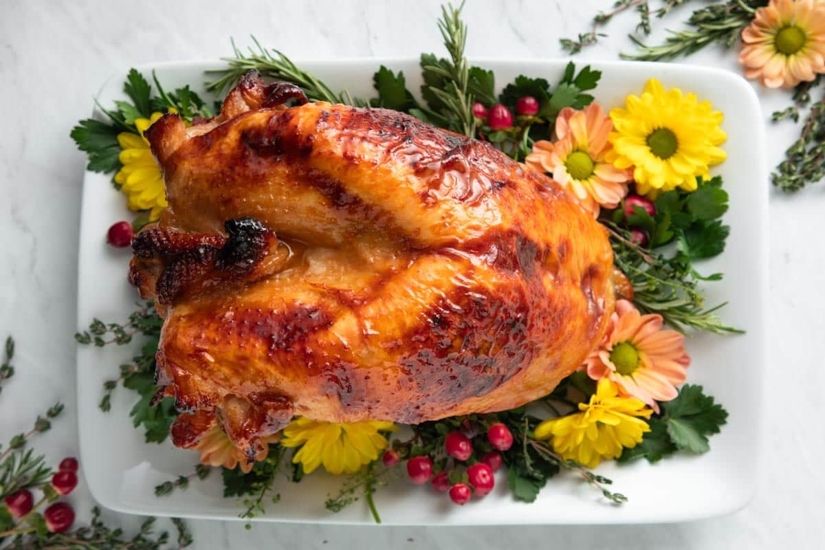 Horizontal overhead shot of a roasted maple glazed whole turkey breast on a white serving platter.
