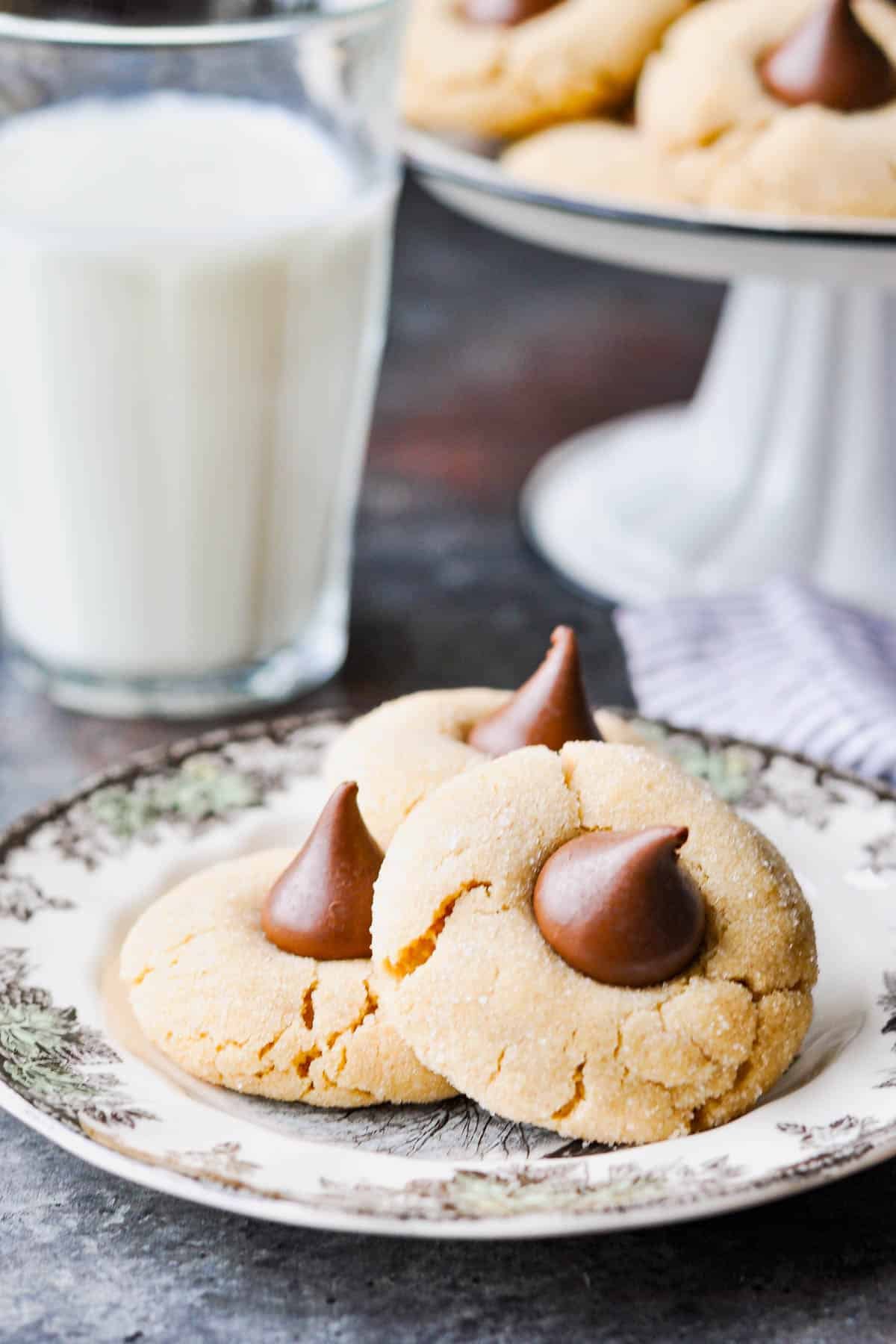 Soft peanut butter blossoms on a table with milk.