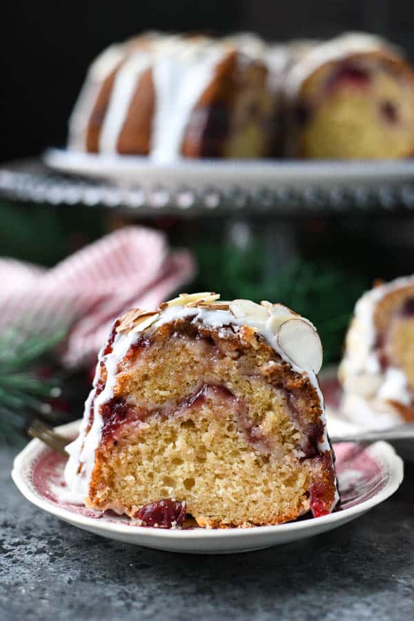 Side shot of a slice of sour cream coffee cake with cranberry swirl on a red and white plate
