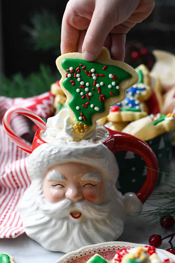 Dipping a cut out sugar cookie in a Santa mug full of hot chocolate