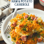 Plate of cheesy ham and potato casserole with text title overlay