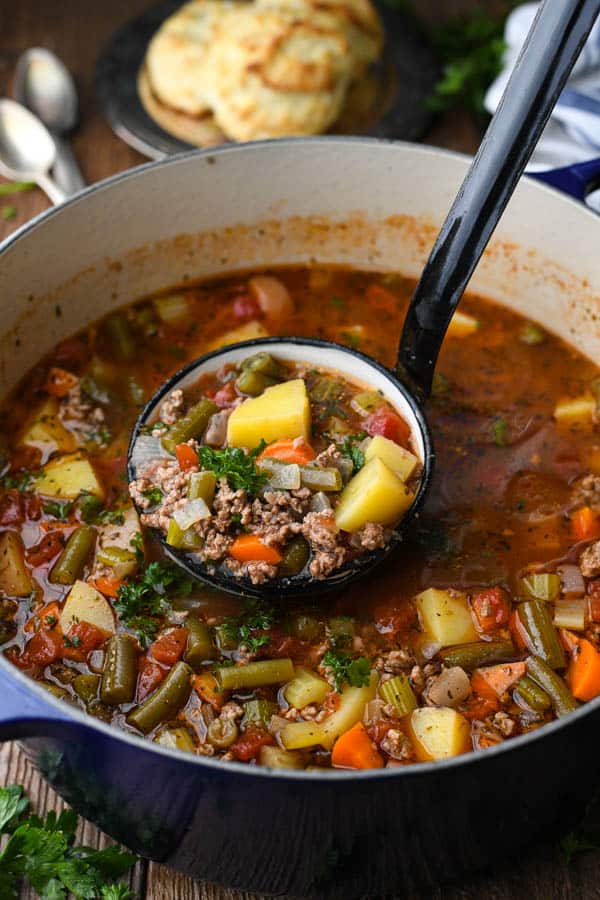 Overhead image of hamburger vegetable soup with a ladle in a big Dutch oven