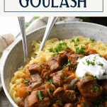 Close up shot of noodles and Hungarian goulash in a bowl with text title box at the top