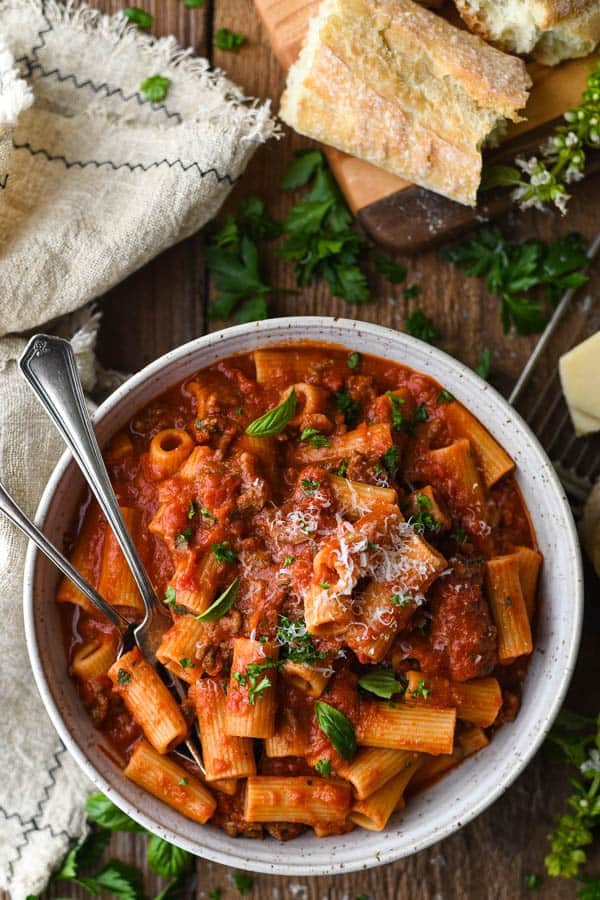 Overhead shot of Italian sausage pasta sauce with rigatoni in a bowl on a wooden table