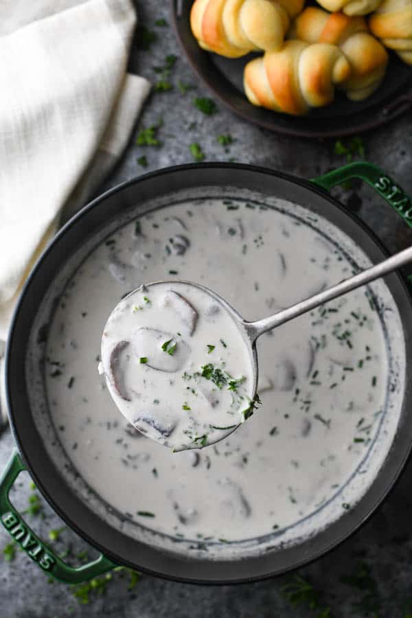 Overhead image of a simple mushroom soup recipe in a Dutch oven with fresh herbs on top