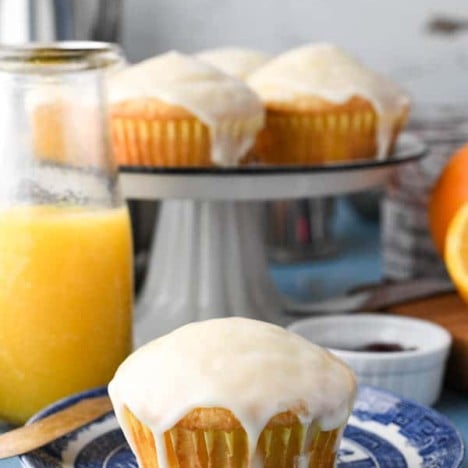 Glaze orange muffin on a blue and white plate with a carafe of orange juice in the background