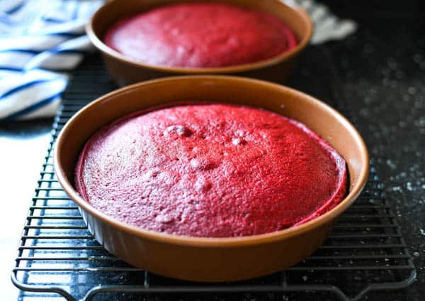 Easy red velvet cake recipe cooling in the pans on a wire rack