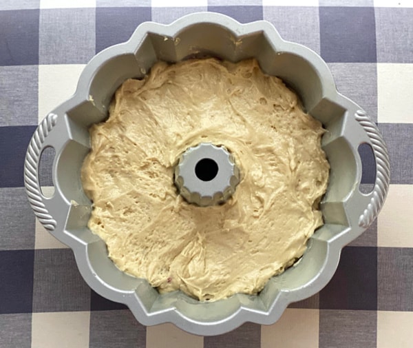 Process shot showing how to spread sour cream coffee cake in a Bundt pan