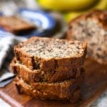 Square image of banana nut bread stacked on a cutting board