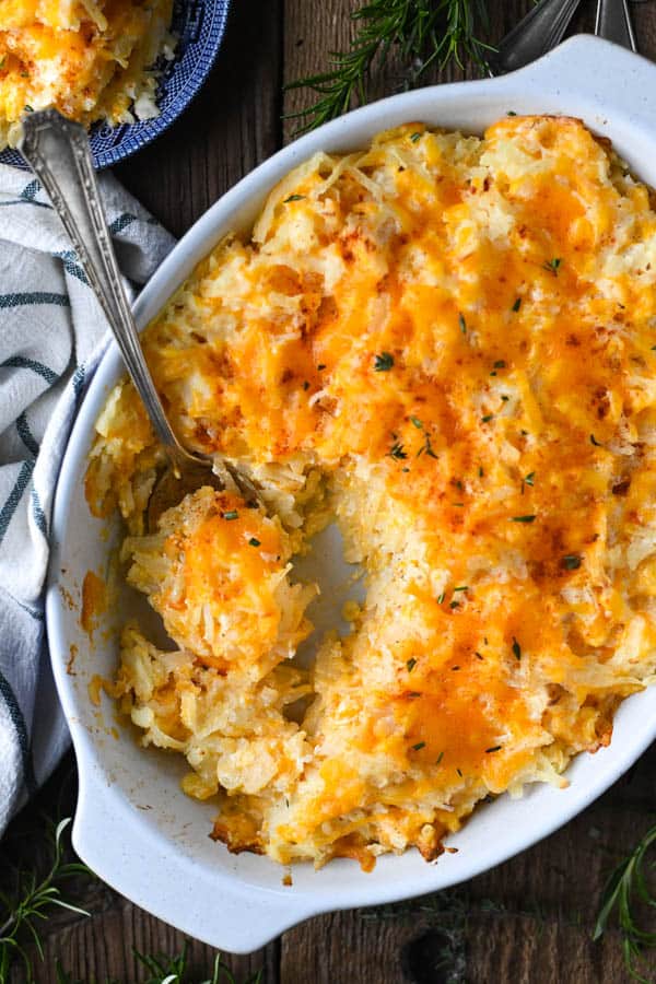 Close overhead shot of a cheesy potato casserole with a serving spoon