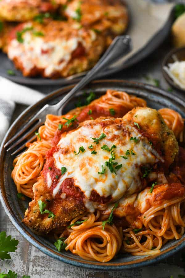 A simple chicken parmesan recipe served with spaghetti in a big bowl