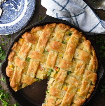 Overhead image of a homemade chicken pot pie on a wooden table with fresh parsley garnish