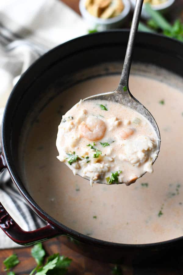 Ladle scooping up crab bisque from a pot