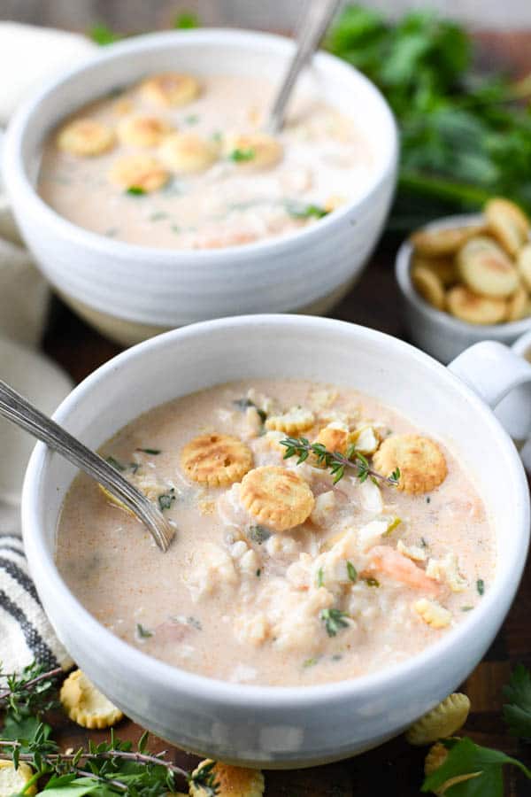 Close up front shot of two bowls of crab bisque served with oyster crackers and fresh parsley