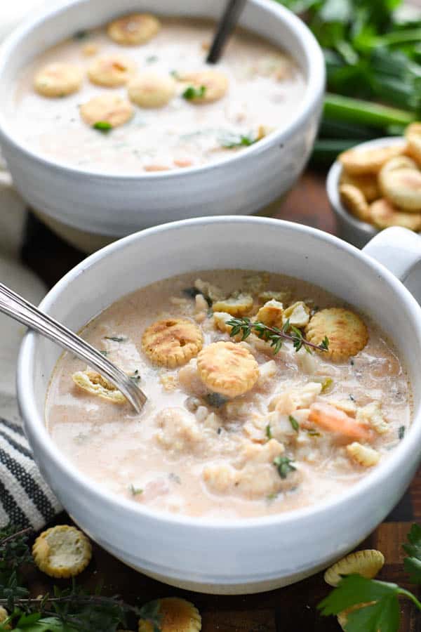 Two bowls full of creamy homemade crab bisque topped with oyster crackers.