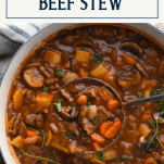 Overhead shot of ladle in a pot of old fashioned beef stew with text title box at top