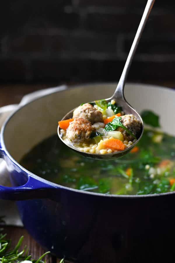 Ladle serving homemade Italian Wedding Soup from a Dutch Oven