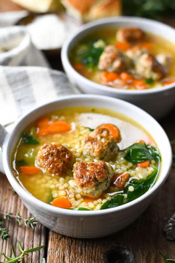 Close side shot of homemade Italian Wedding Soup recipe served in two handmade white ceramic bowls