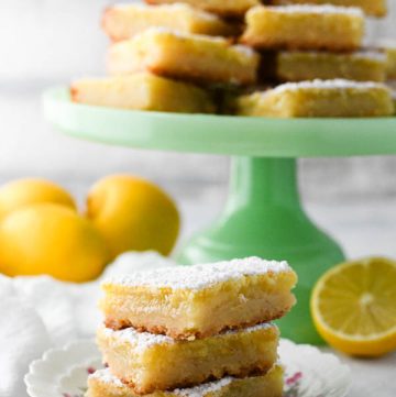 Side shot of a small plate full of the best lemon squares stacked