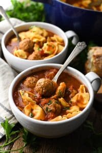 Side shot of two bowls of tortellini and meatball soup on a table
