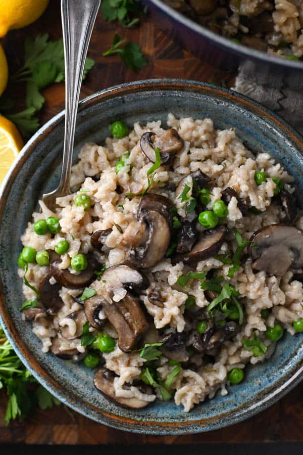 Close overhead shot of a bowl of mushroom pea risotto with a fork in it