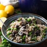 Mushroom and parmesan risotto recipe in a blue ceramic bowl with parsley garnish