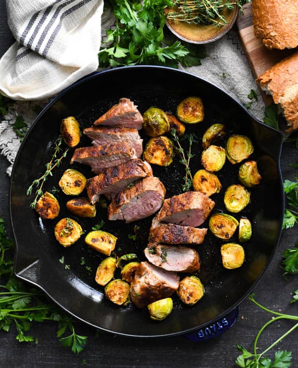BBQ pork tenderloin in a skillet with crispy Brussels sprouts