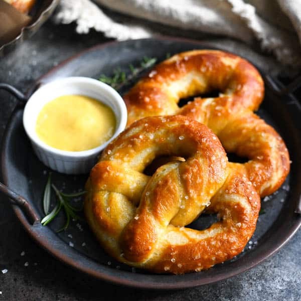 Square shot of two easy soft pretzels on a plate with mustard