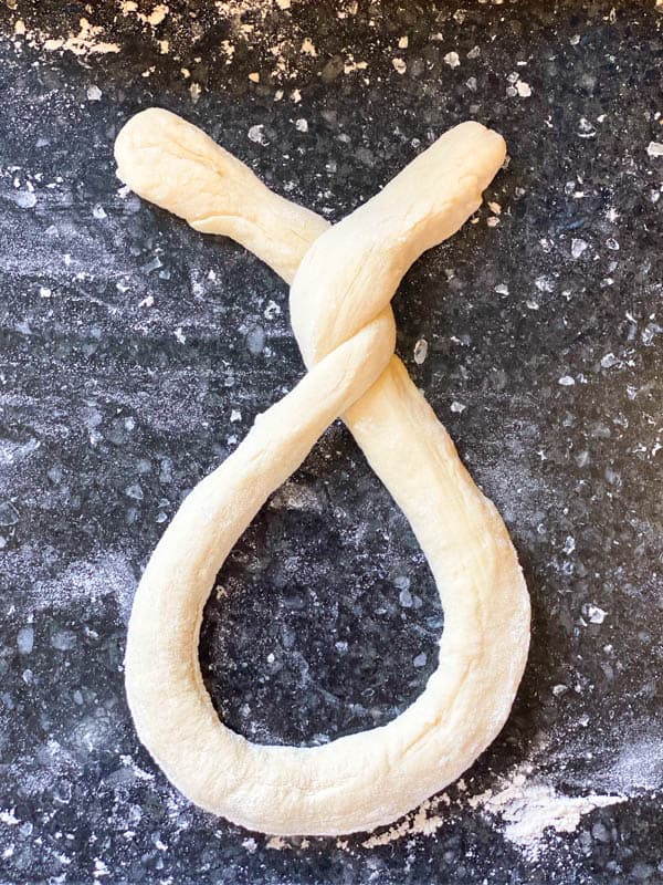 Process shot showing how to shape homemade soft pretzel recipe