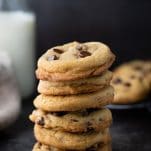 Stack of soft and chewy chocolate chip cookies on a dark surface