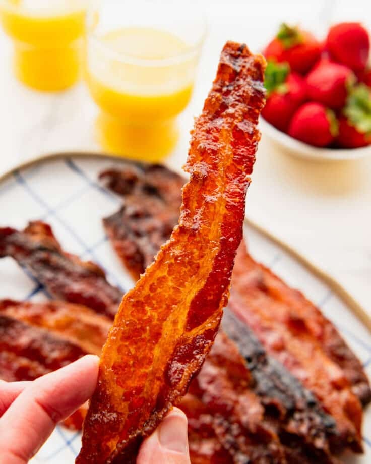 Hands holding a strip of crispy pig candy.