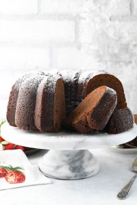 Front shot of sliced chocolate pound cake on a white cake stand