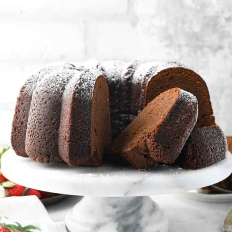 Front shot of sliced chocolate pound cake on a white cake stand