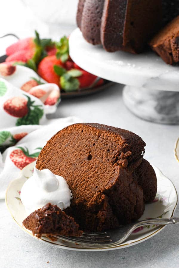 Close up shot of moist chocolate pound cake on a plate with whipped cream