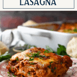 Side shot of sausage lasagna on a plate with text title box at top