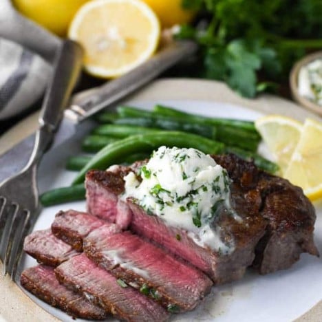 Sliced filet mignon on a plate with garlic herb butter