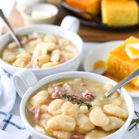 Side shot of two bowls of butter beans with ham and cornbread