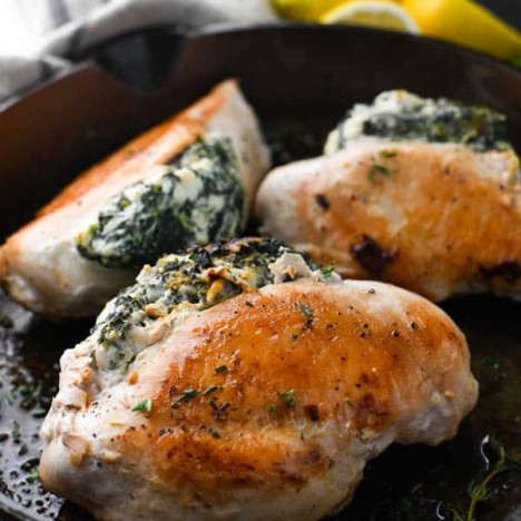 Front shot of spinach stuffed chicken breasts in a cast iron skillet