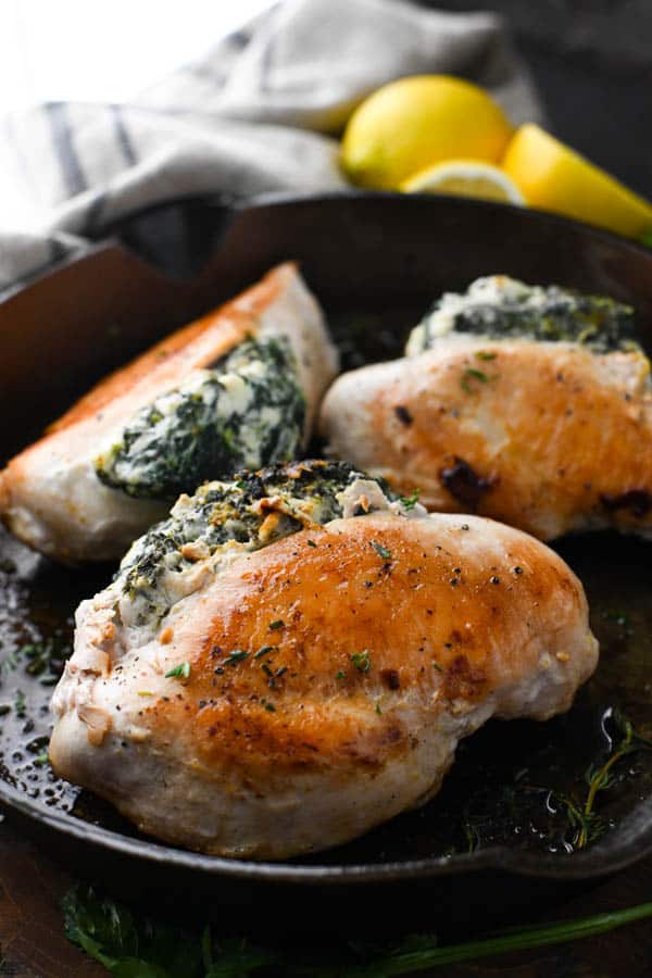 Front shot of spinach stuffed chicken breasts in a cast iron skillet