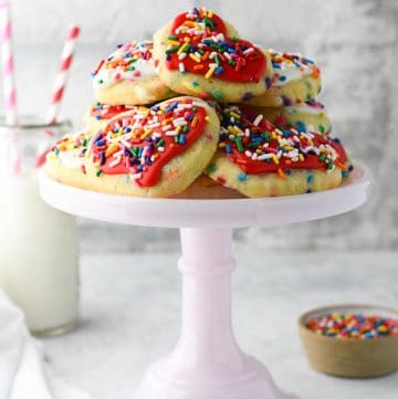 Side shot of a pink cake stand full of sugar cookies with sprinkles